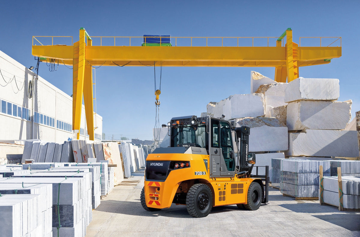 Hyundai 70B-X el-gaffeltruck på en stenplads med marmorblokke under en portalkran